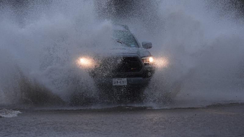 A vehicle navigates a flooded roadway as heavy rain move through the area, in San Antonio,...