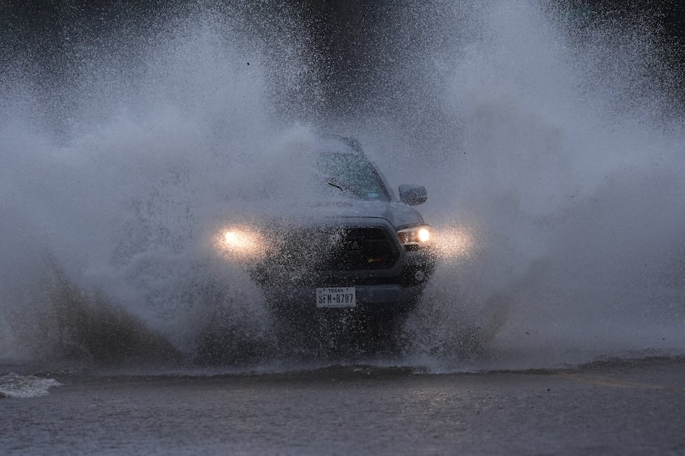 A vehicle navigates a flooded roadway as heavy rain move through the area, in San Antonio,...