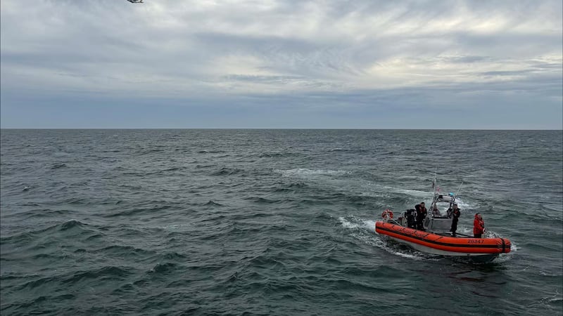 In this photo released by U.S. Coast Guard, crew members search by air and on the water for a...